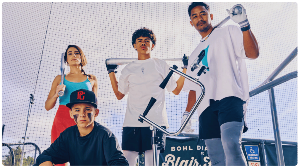 Group of baseball players of all ages posing with the best batting tee for young baseball players at Bohl Diamond, ready for swing training and skill development.