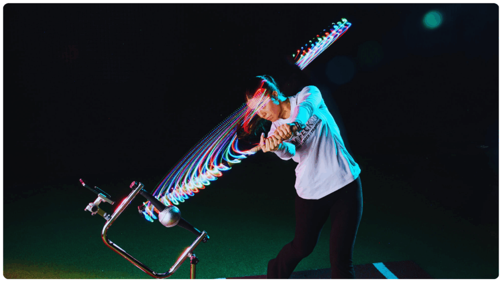 High school softball player using the best batting tee for high school players, with a motion trail effect capturing bat swing speed and accuracy during night training.
